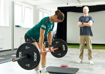 Sportlerin an der Langhantel mit Personal Trainer und Physiotherapeut Malte Klett